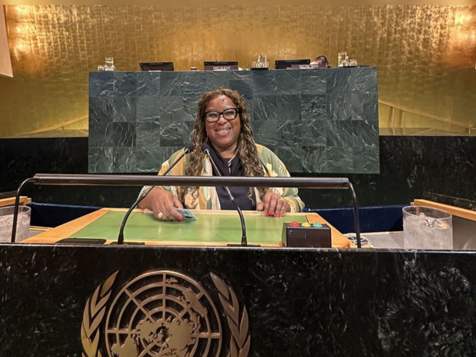 Ministra Macaé, mulher negra, sorrindo na bancada principal da Assembleia Geral da ONU.