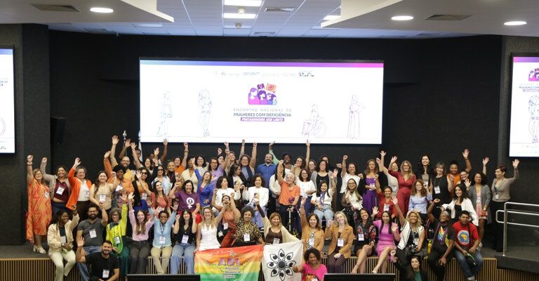 Grupo diverso de mulheres com deficiência reunidas em evento, celebrando inclusão e protagonismo.