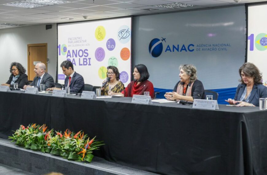 Mesa de conferência da ANAC com sete pessoas e cartaz sobre 10 anos da LBI ao fundo.