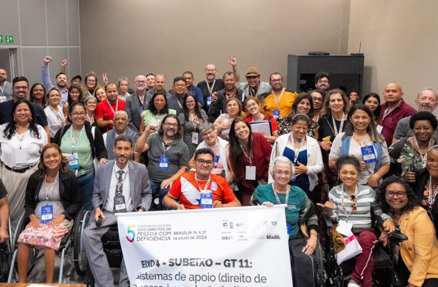 Grupo diverso sorrindo em conferência sobre direitos da pessoa com deficiência, em Brasília.