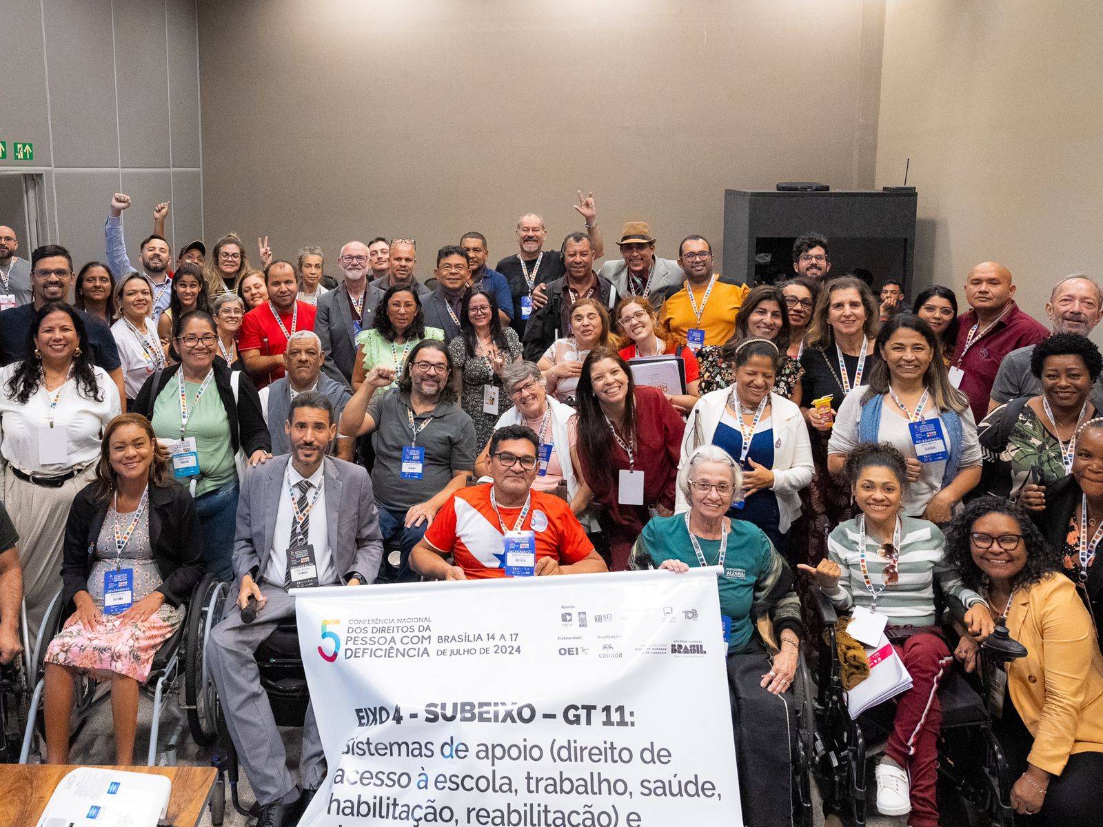 Grupo diverso sorrindo em conferência sobre direitos da pessoa com deficiência, em Brasília.