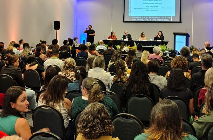 Auditório cheio com pessoas assistindo a um painel de debates sobre educação especial.