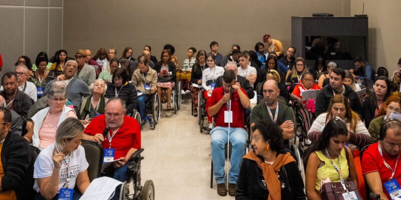 Auditório cheio com pessoas com deficiência participando de um evento inclusivo e acessível.