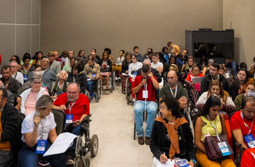Auditório cheio com pessoas com deficiência participando de um evento inclusivo e acessível.