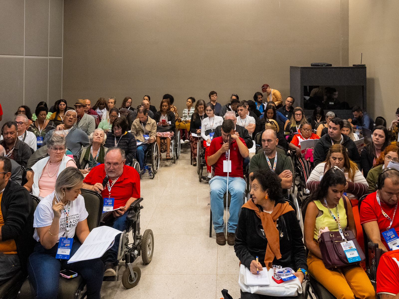Auditório cheio com pessoas com deficiência participando de um evento inclusivo e acessível.