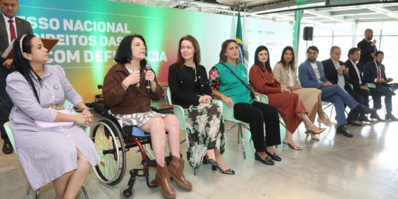 Grupo diverso em evento sobre direitos das pessoas com deficiência, destaque para mulher cadeirante.
