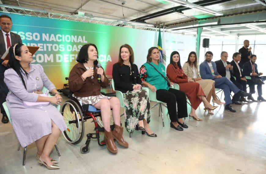 Grupo diverso em evento sobre direitos das pessoas com deficiência, destaque para mulher cadeirante.