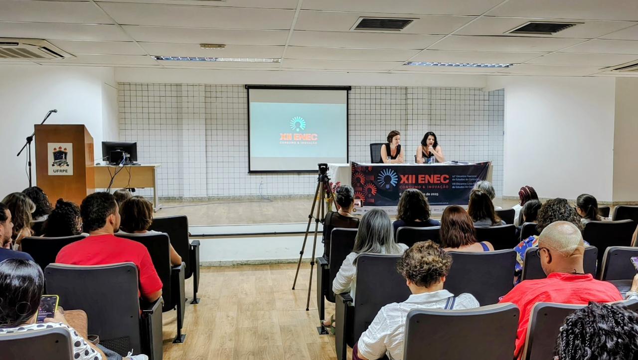 Pessoas assistem a duas palestrantes no palco durante o XII ENEC na universidade UFRPE.
