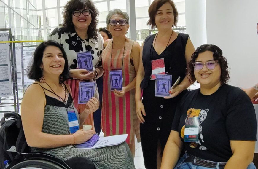 Cinco mulheres sorrindo, segurando cordéis roxos com desenho de cadeirante e a palavra CORDEL.