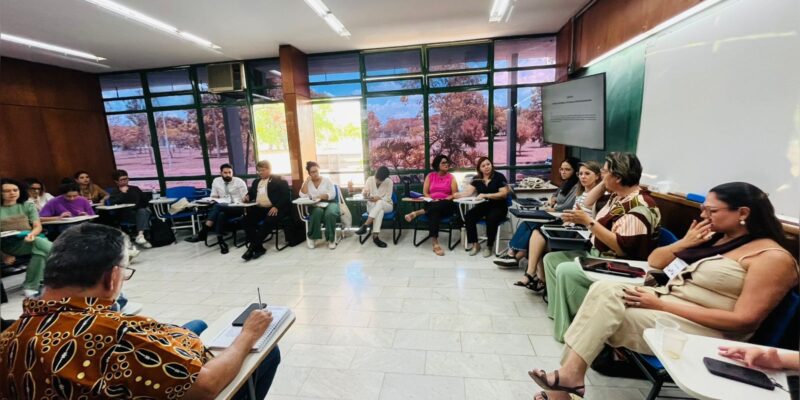 Grupo de pessoas sentadas em círculo numa sala, participando de uma roda de conversa animada.