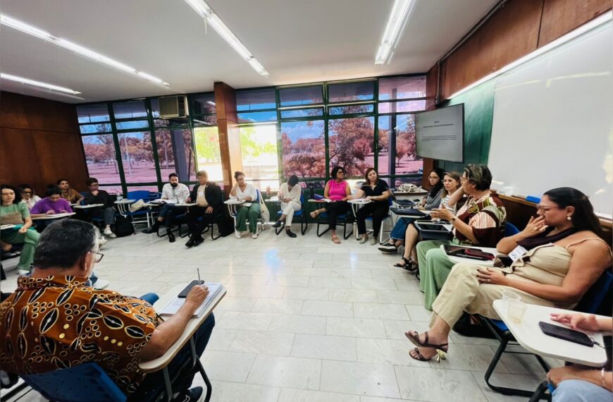 Grupo de pessoas sentadas em círculo numa sala, participando de uma roda de conversa animada.