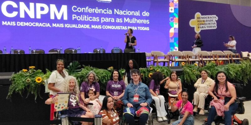 Grupo de mulheres com deficiência reunidas no palco da 5ª Conferência Nacional das Mulheres.