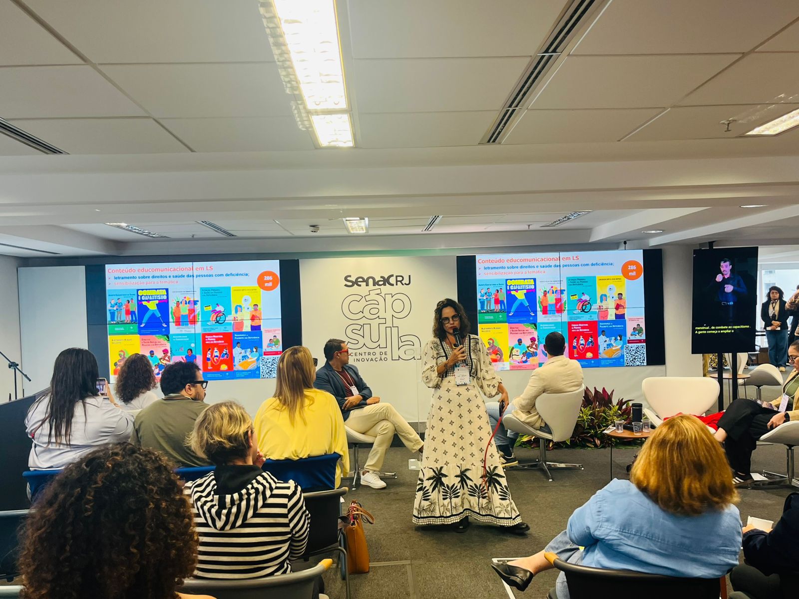 Pessoas assistem palestra inclusiva com intérprete de Libras e conteúdos sobre saúde e direitos.