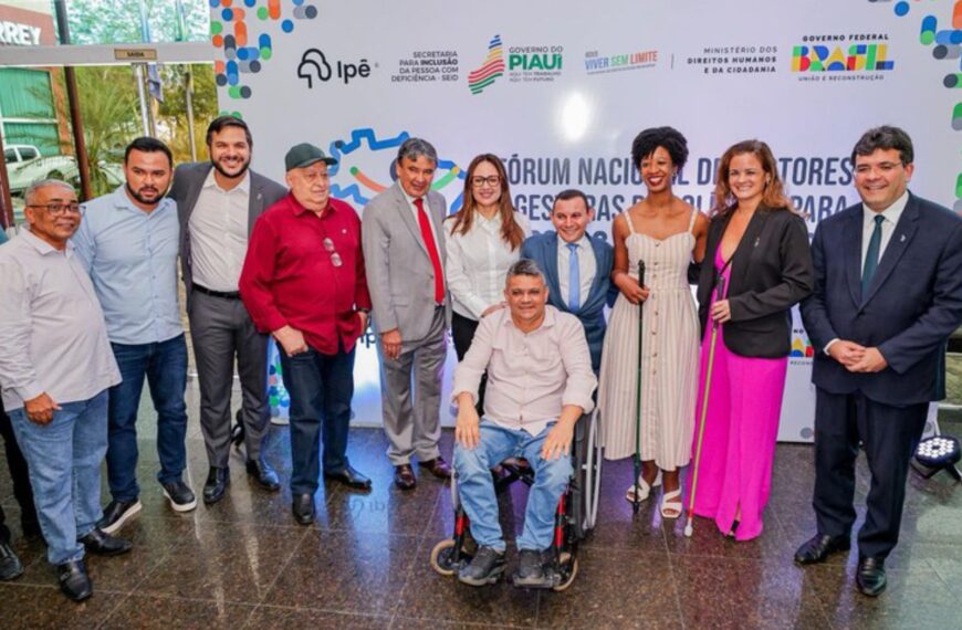 Grupo diverso posa sorrindo em evento de inclusão do Governo do Piauí. Destacam-se um homem em cadeira de rodas e duas mulheres com bengalas para deficientes visuais. Clima de celebração.