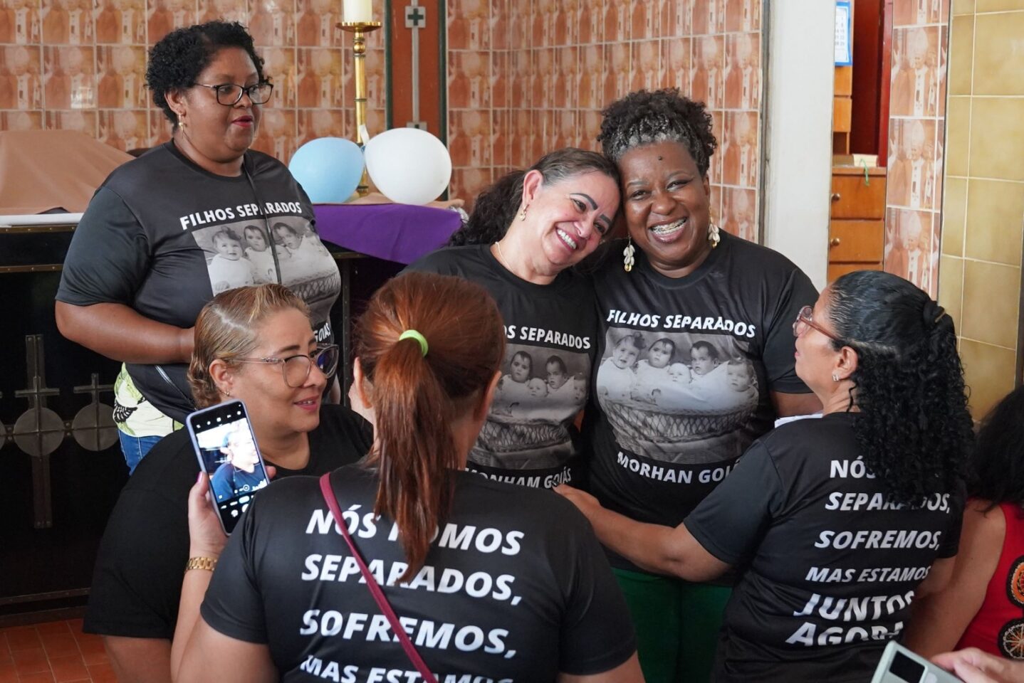 Grupo de seis mulheres incluindo a Ministra do MDHC Macaé com camisetas “FILHOS SEPARADOS”, sorrindo e se abraçando
