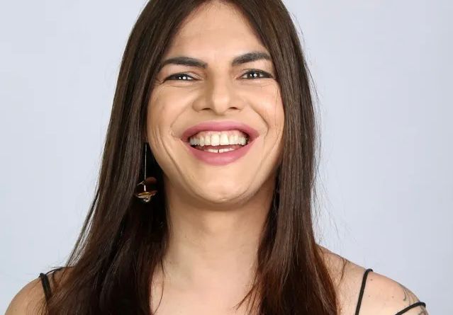 Histórias de vida e pertencimento: pessoas trans com deficiência fortalecem a mobilização por direitos no Brasil Close do rosto de mulher sorrindo; batom rosa; cabelo longo castanho.